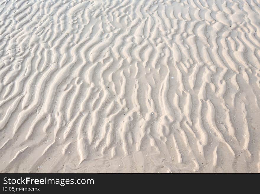 Wet sand by sea water texture.