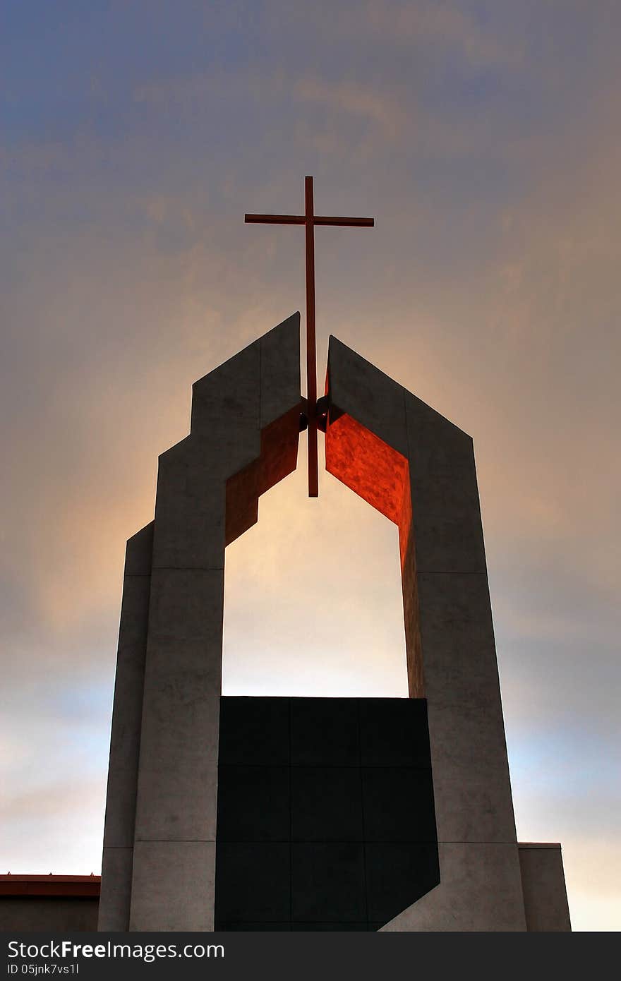 This photo of a church steeple with a cross on the very top was taken just as the sun was going down. The light from the setting sun was reflected off the inside of where the cross was attached and the timing of the photo still provided some blue sky and colorful clouds. This photo of a church steeple with a cross on the very top was taken just as the sun was going down. The light from the setting sun was reflected off the inside of where the cross was attached and the timing of the photo still provided some blue sky and colorful clouds.