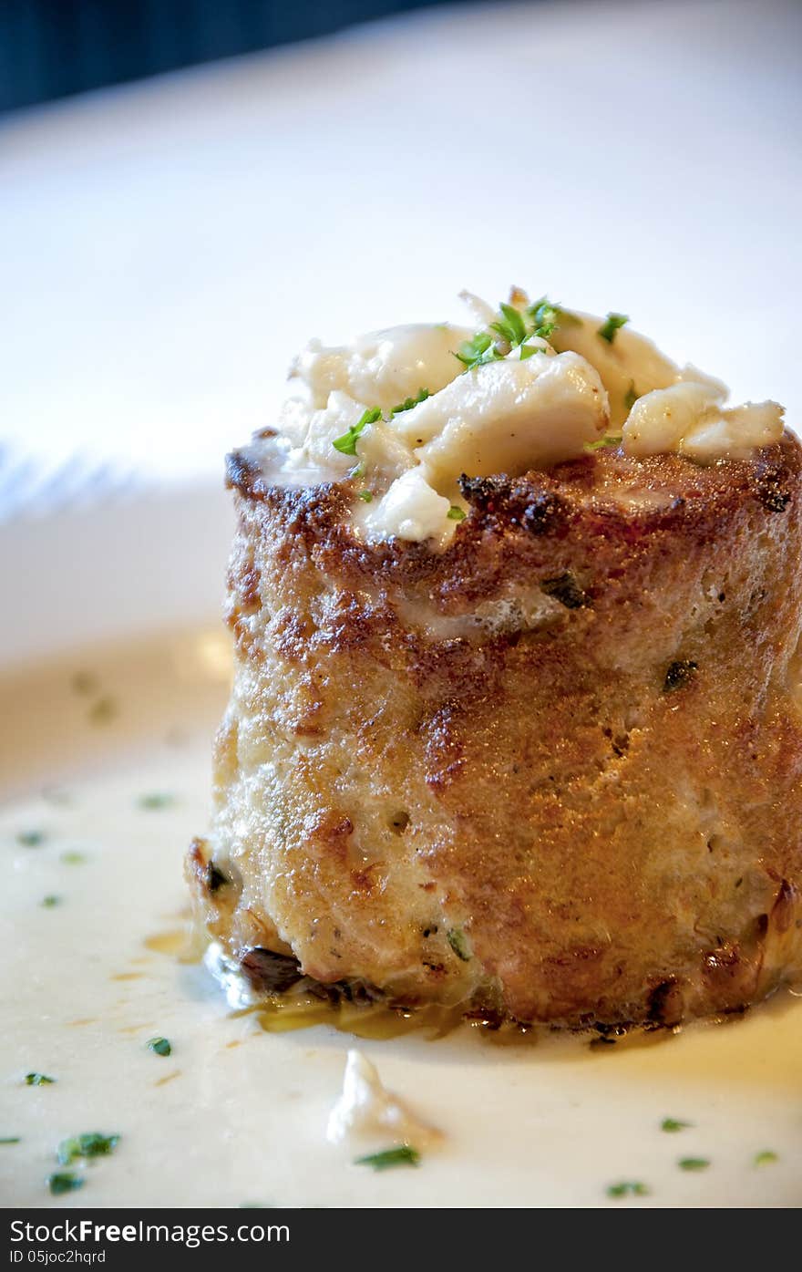 This is a off center, close up picture of a crab cake with bits of crab on top.