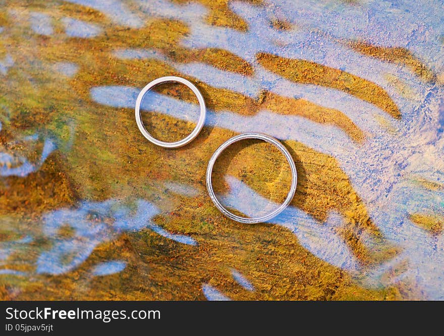 Wedding rings in water with reflections