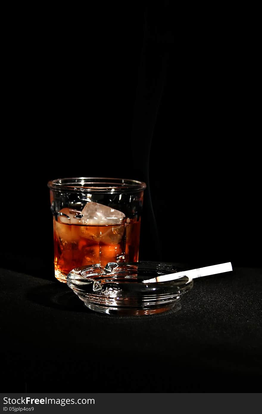 Cigarette next to a glass of brandy. Cigarette next to a glass of brandy