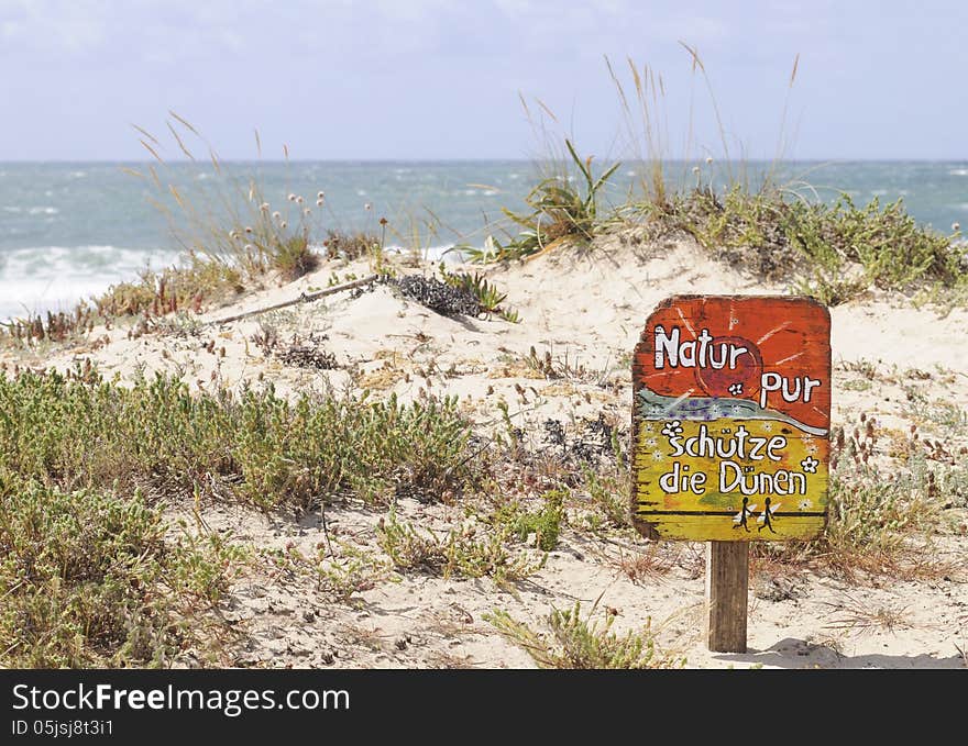 Nature is pure. Protect the dunes. (or Nature pur. Schütze die dunen) - Wooden sign, for german tourists, on a dune beach in Peniche, Portugal. Peniche is one of the best surfing locations in Europe. It has beaches and breaks facing in 3 distinctly different directions. Recently it has become one of the destination for the WCT of the ASP or World championship tour of Association of surfing professionals.