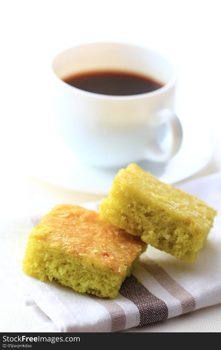 Coconut pandan cake and a cup of coffee in the background