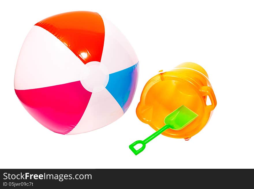 Beach ball and sand pail ready to take to the beach on vacation. Horizontal shot, isolated on a white background. Beach ball and sand pail ready to take to the beach on vacation. Horizontal shot, isolated on a white background