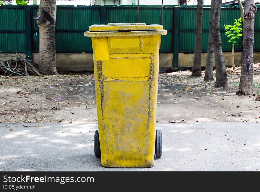 Old yellow recycling bin on concrete