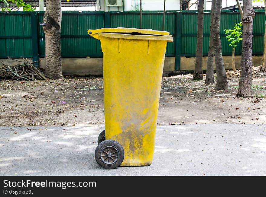 Old yellow recycling bin on concrete