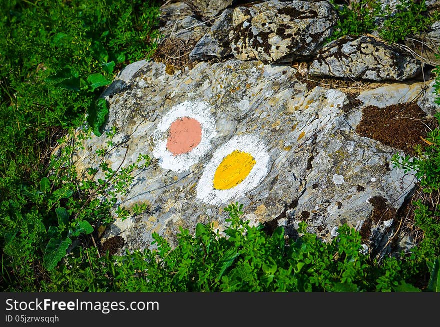 Yellow and red trail sign painted on a mountain rock. Yellow and red trail sign painted on a mountain rock