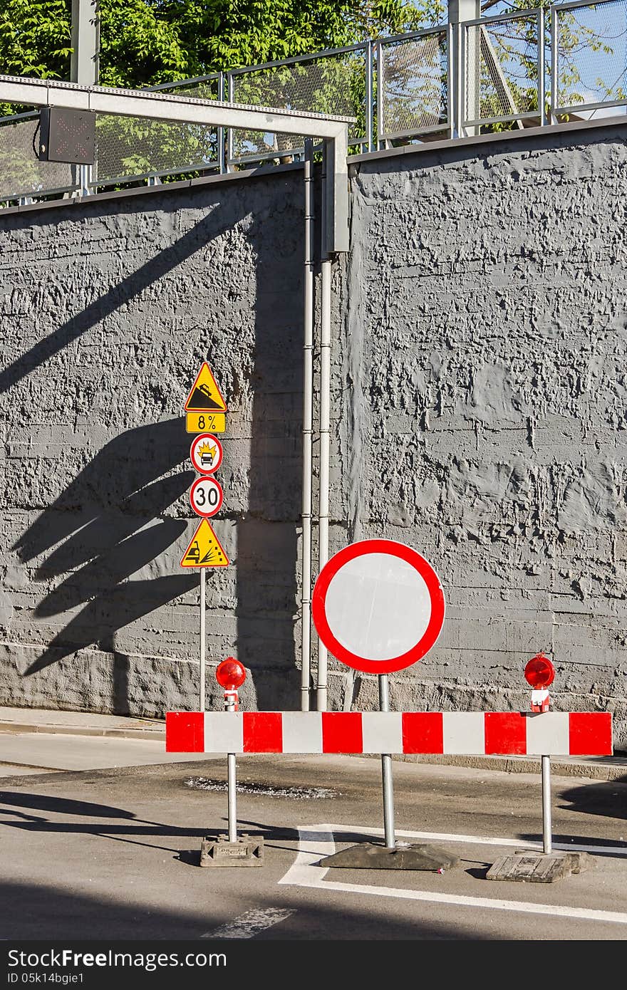 Road signs against a grey wall.