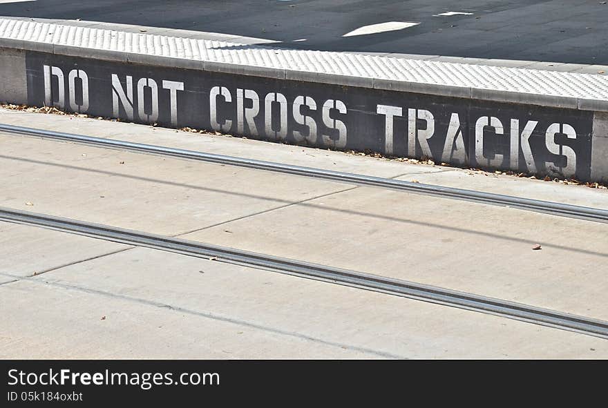 Sign on public train transit warning people not to cross the tracks. Sign on public train transit warning people not to cross the tracks.