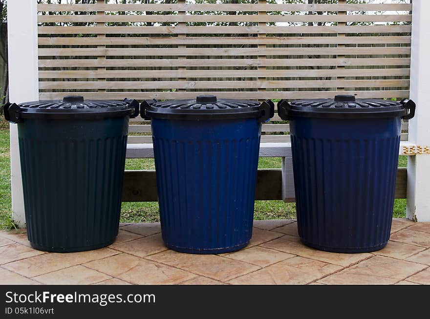 Three waste containers in the street.