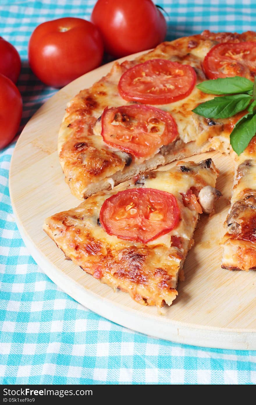 Tasty vegetarian pizza with cheese, tomatoes and mushrooms on a wooden board. Tasty vegetarian pizza with cheese, tomatoes and mushrooms on a wooden board