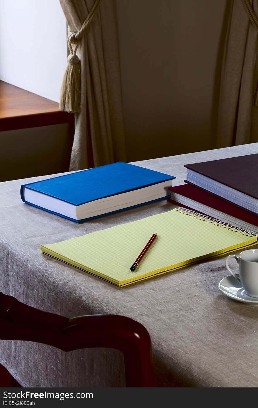 Notebook on the table with a pencil and books