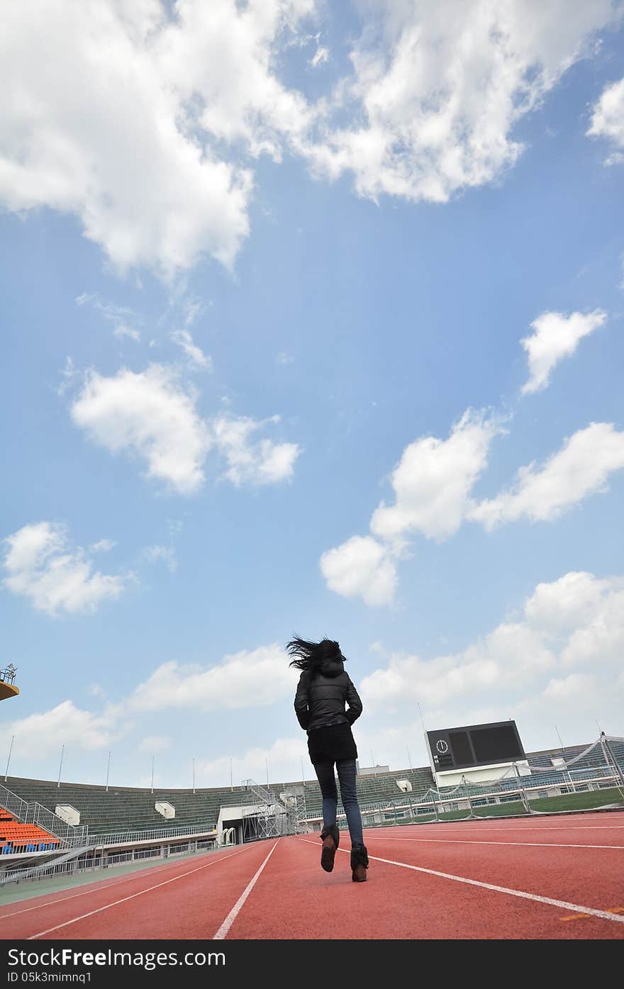 Back portrait of single young girl running in stadium