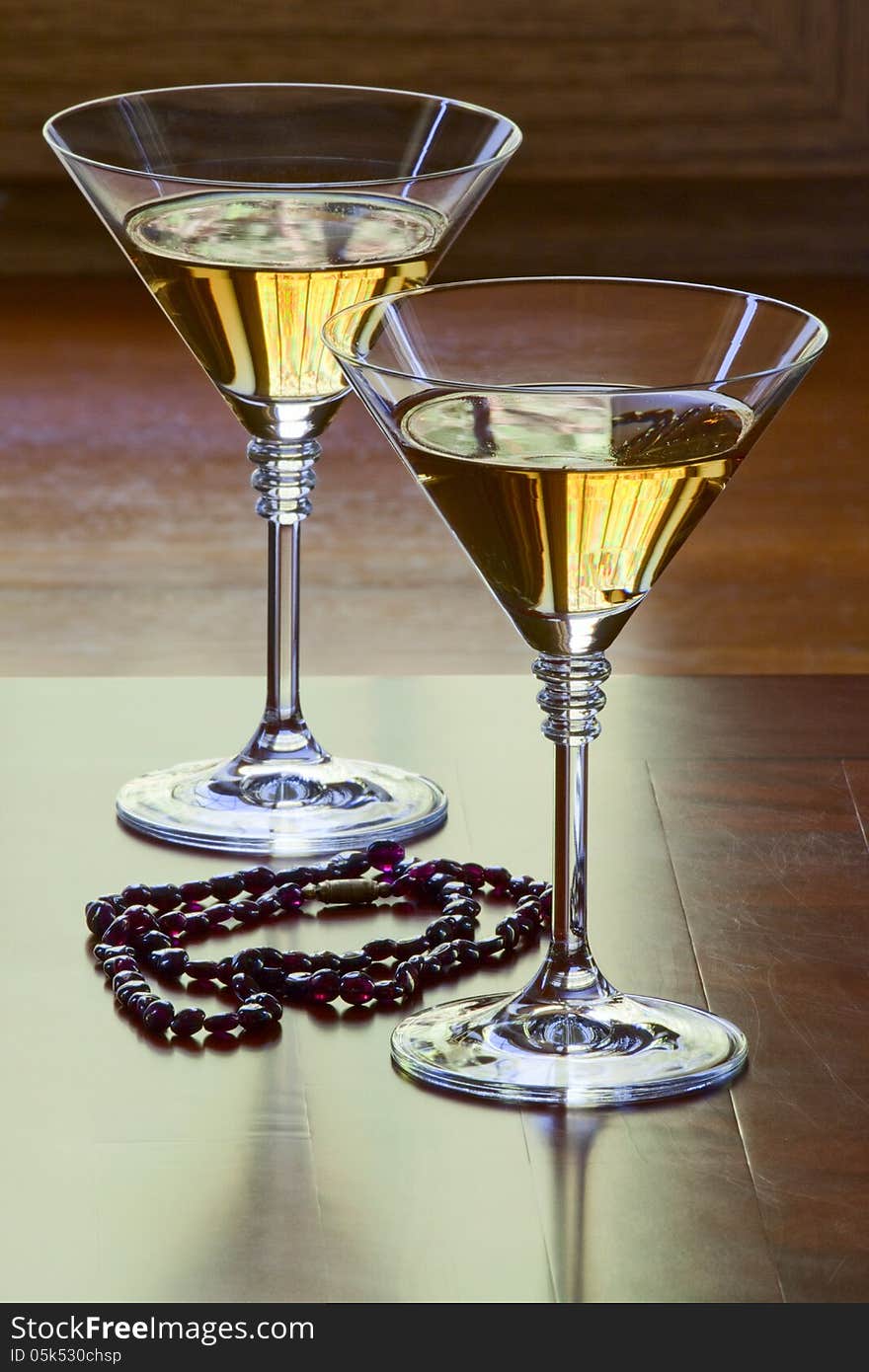 Garnet necklace and two glasses with white wine on an old table. Garnet necklace and two glasses with white wine on an old table