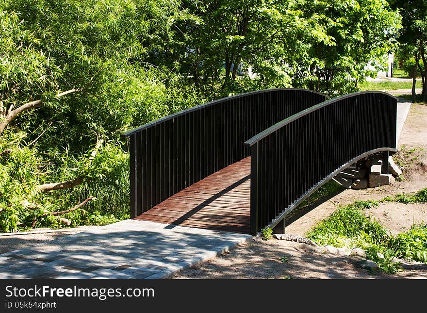 Pedestrian bridge in city park on sunny summer day