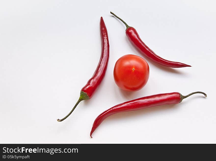 Three Chili And One  Tomato On A White Background.