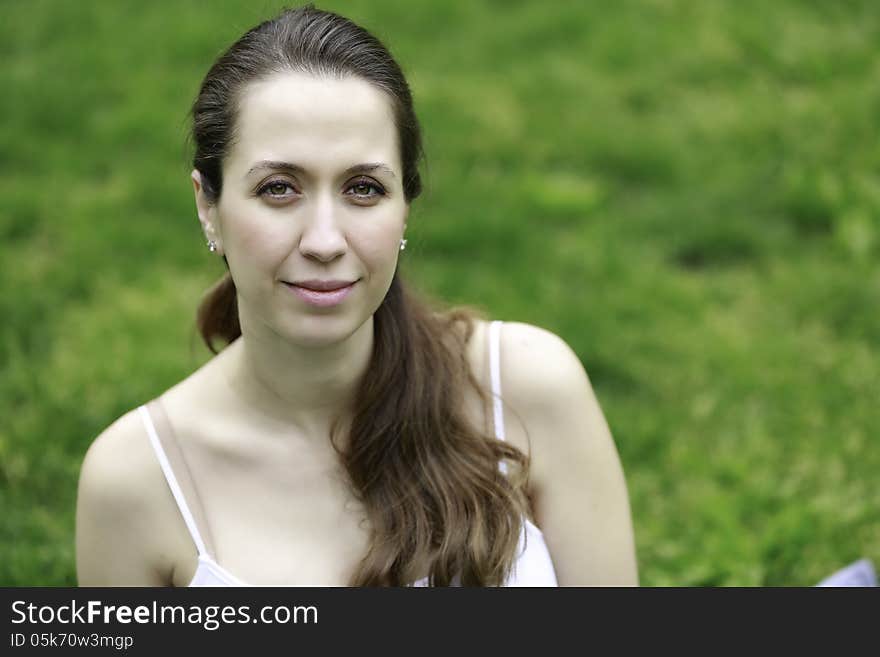 Closeup portrait of gorgeous young female sitting confidently against a green grass backdrop