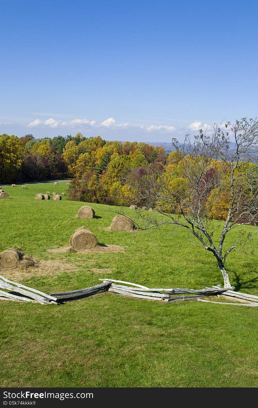 Old fence near a field with bales of hay.