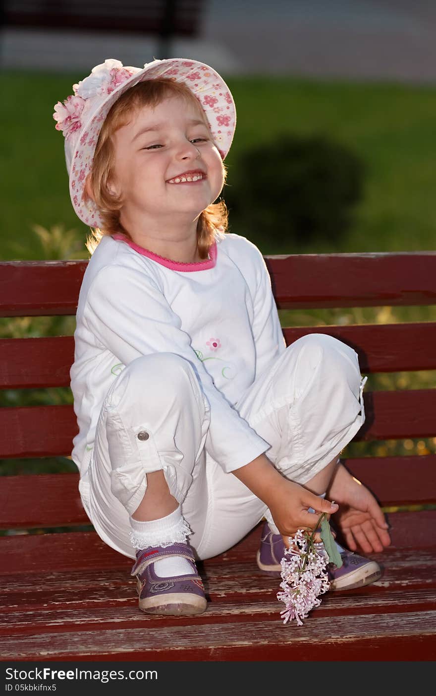 Portrait of the girl in park on a bench.