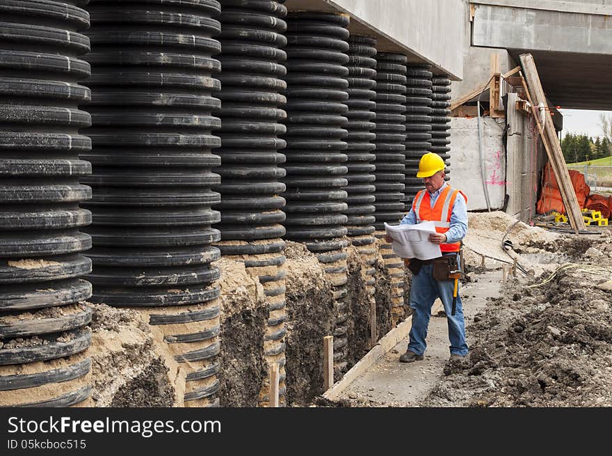 Bridge construction worker checking blueprint at job site