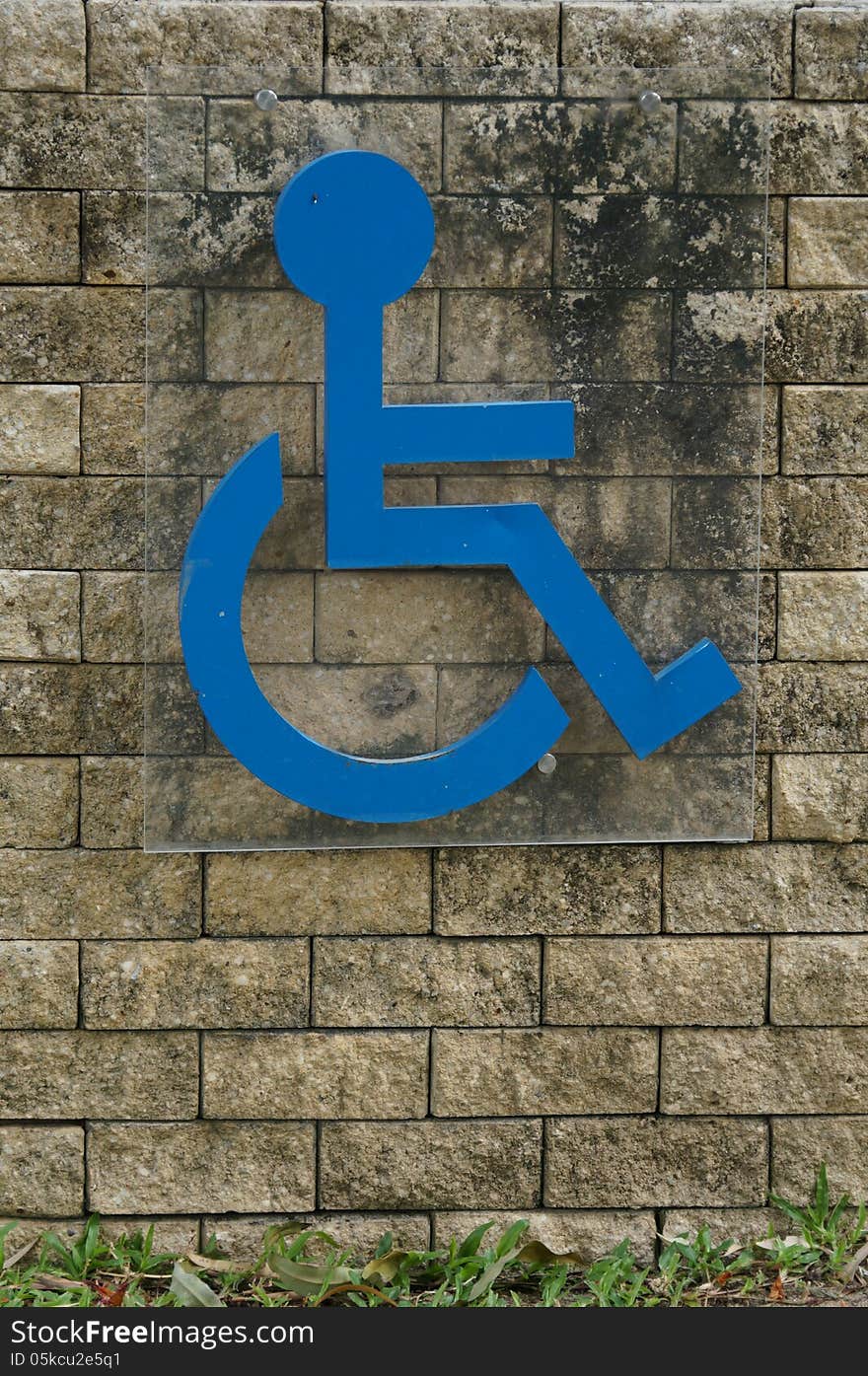 Blue sign of a handicap accessible sign on a brick wall