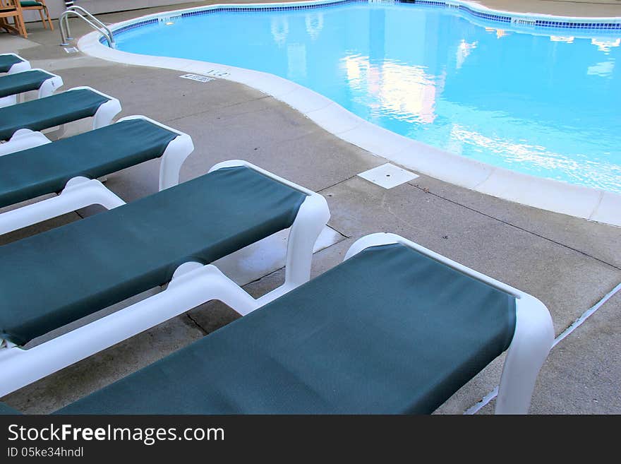 Deep blue lounge chairs set near the pool side,inviting swimmers to relax after their laps in the water. Deep blue lounge chairs set near the pool side,inviting swimmers to relax after their laps in the water.