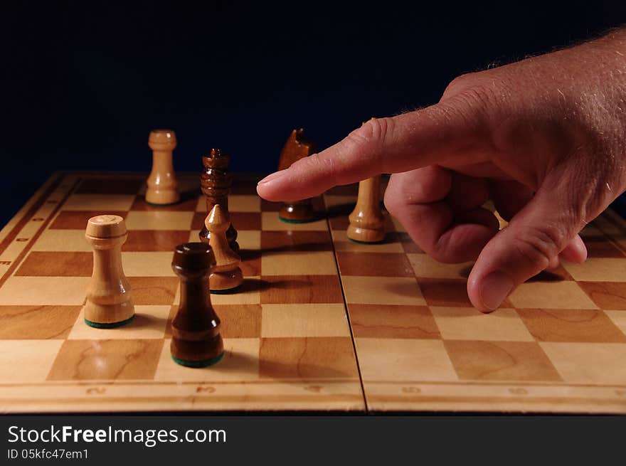 The picture shows the board game of chess, in which the figures of chess. Of the board's hand is stretched out in the direction of one of the figures. The picture shows the board game of chess, in which the figures of chess. Of the board's hand is stretched out in the direction of one of the figures.