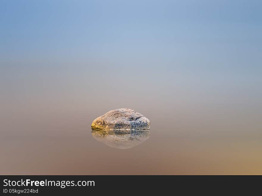 Abstract image with motion blurred sea, sky and stone