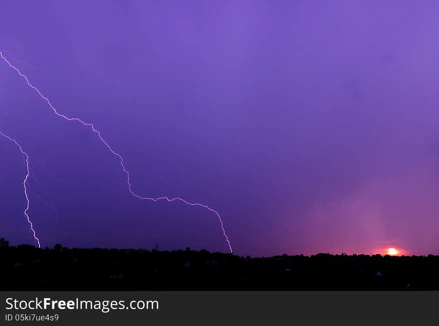 Lightning at sunset on the background of dark blue, purple clouds in the city