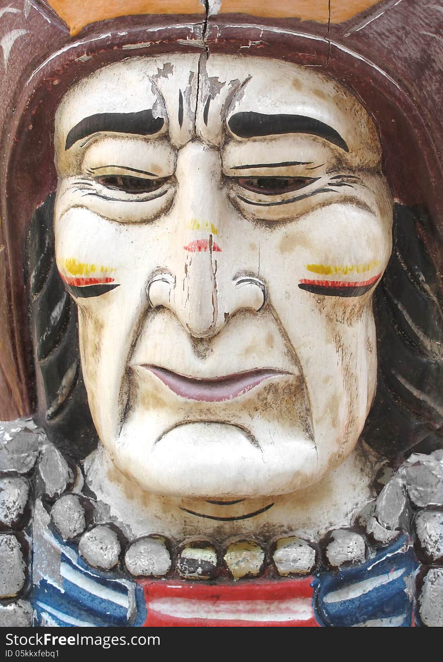 Close-up of an old wooden carved and painted face of a North American Indian man. Close-up of an old wooden carved and painted face of a North American Indian man.