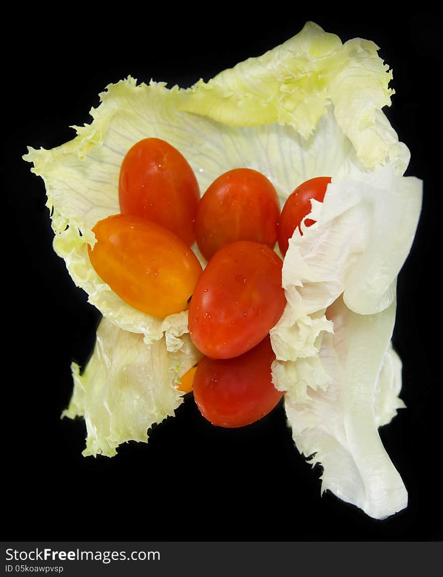 Cabbage leaf with red ripe tomatoes isolated on black. Cabbage leaf with red ripe tomatoes isolated on black