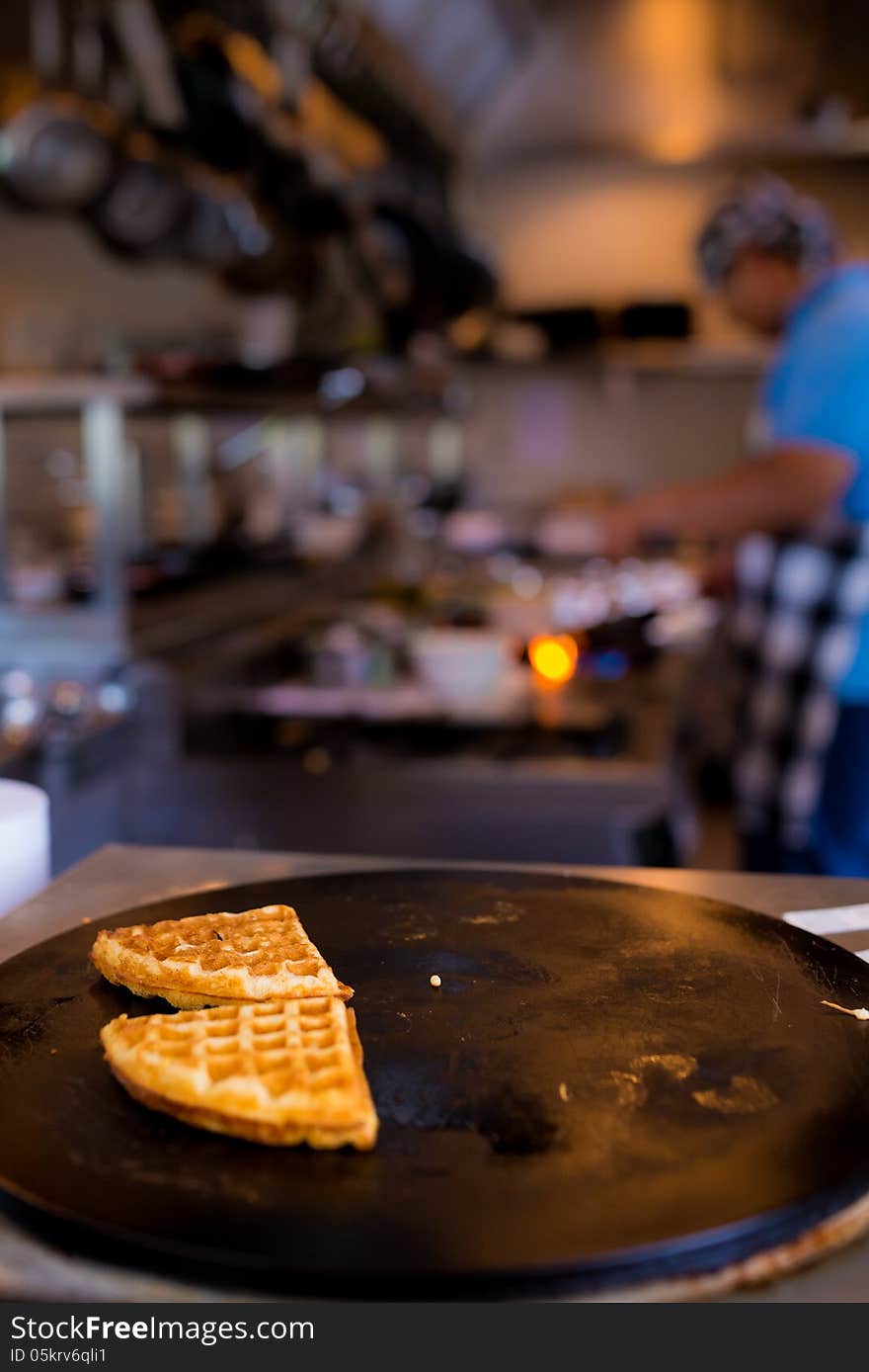 Fresh Piece Of Waffles On Black Plate With Blurred Cooking Chef In Background