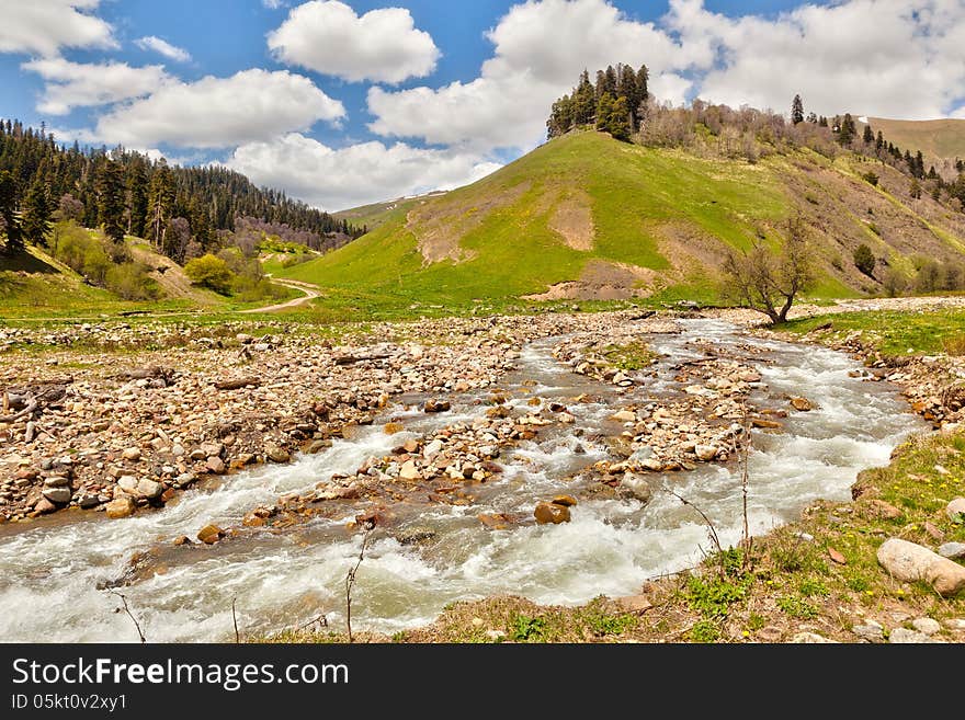 View to the foothills of the Caucasus mountains over stream near Arkhyz, Karachay-Cherkessia, Russia. View to the foothills of the Caucasus mountains over stream near Arkhyz, Karachay-Cherkessia, Russia