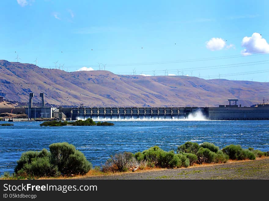 The John Day Dam on the Columbia River with area view of the Washington hills under white fluffy clouds overhead. The John Day Dam on the Columbia River with area view of the Washington hills under white fluffy clouds overhead.