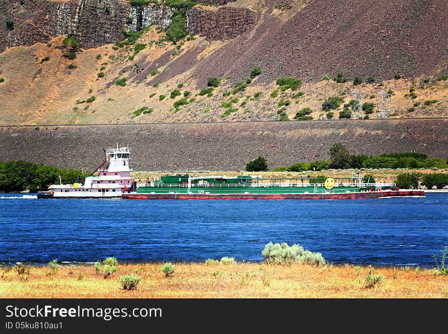 A tug boat pushing a barge in the traffic lane in the Columbia River Gorge. Common daily scene. A tug boat pushing a barge in the traffic lane in the Columbia River Gorge. Common daily scene.