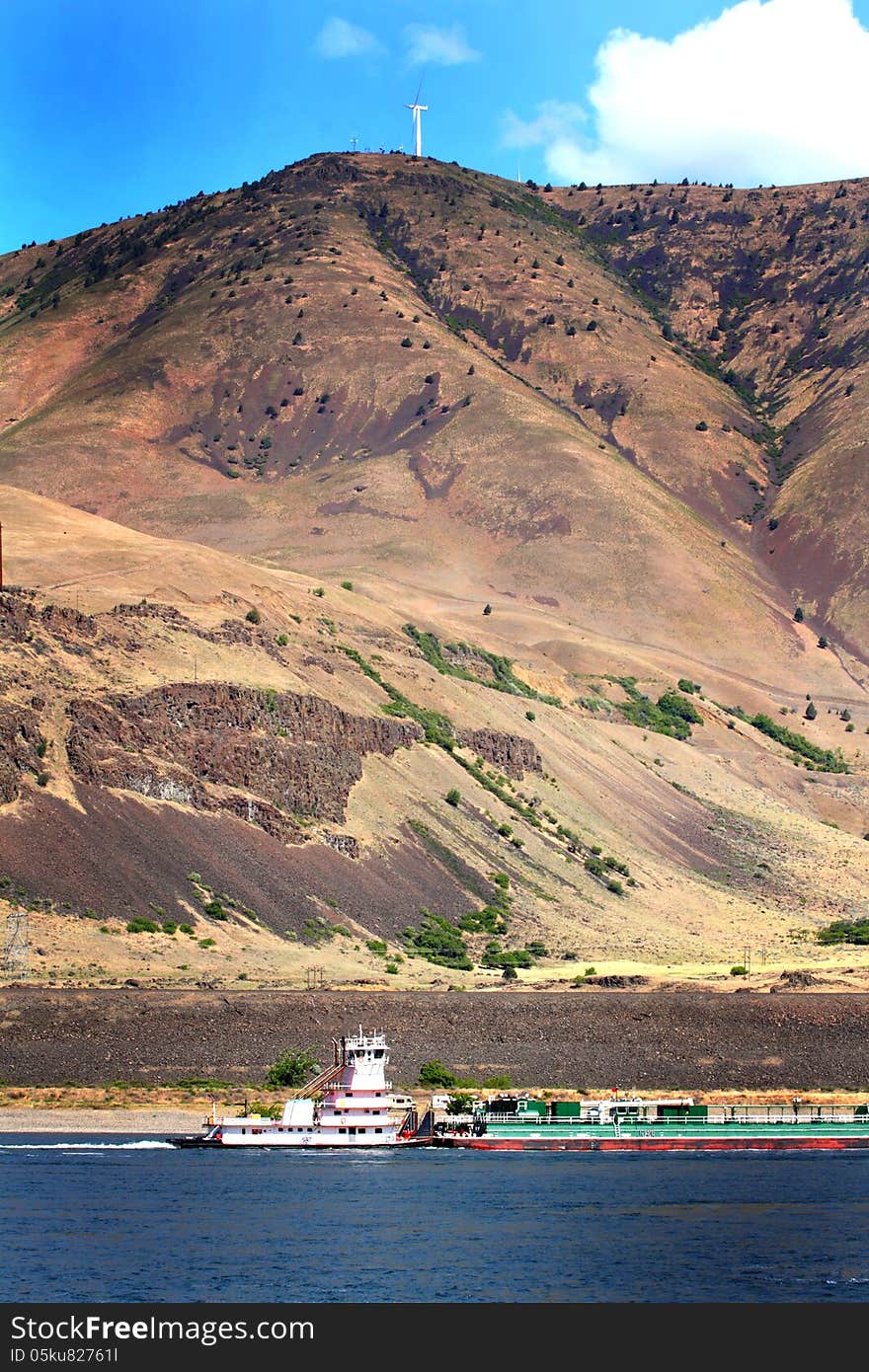 A tug boat pushing a barge in the traffic lane in the Columbia River Gorge. Common daily scene. A tug boat pushing a barge in the traffic lane in the Columbia River Gorge. Common daily scene.