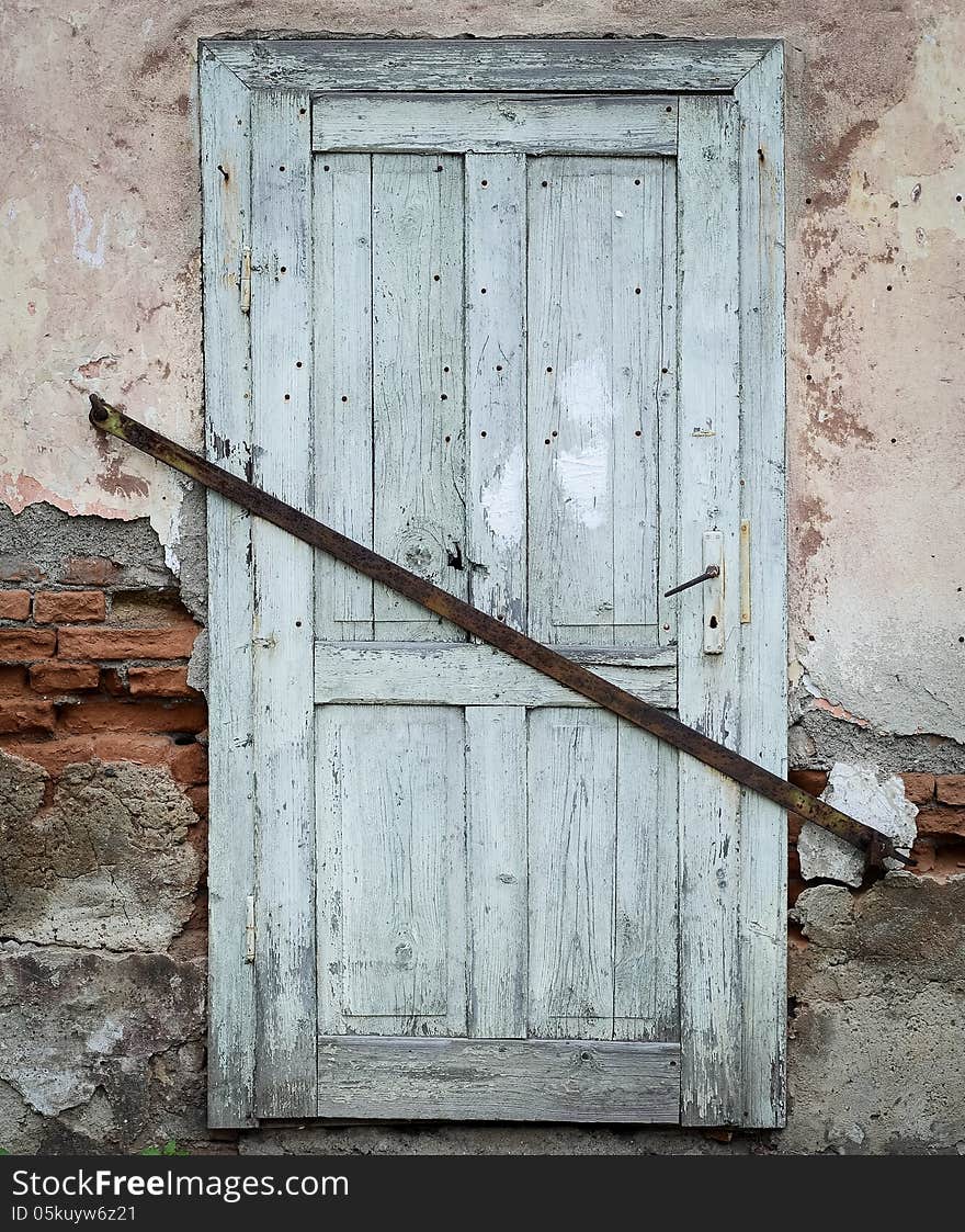 Old wooden door locked with a iron joist