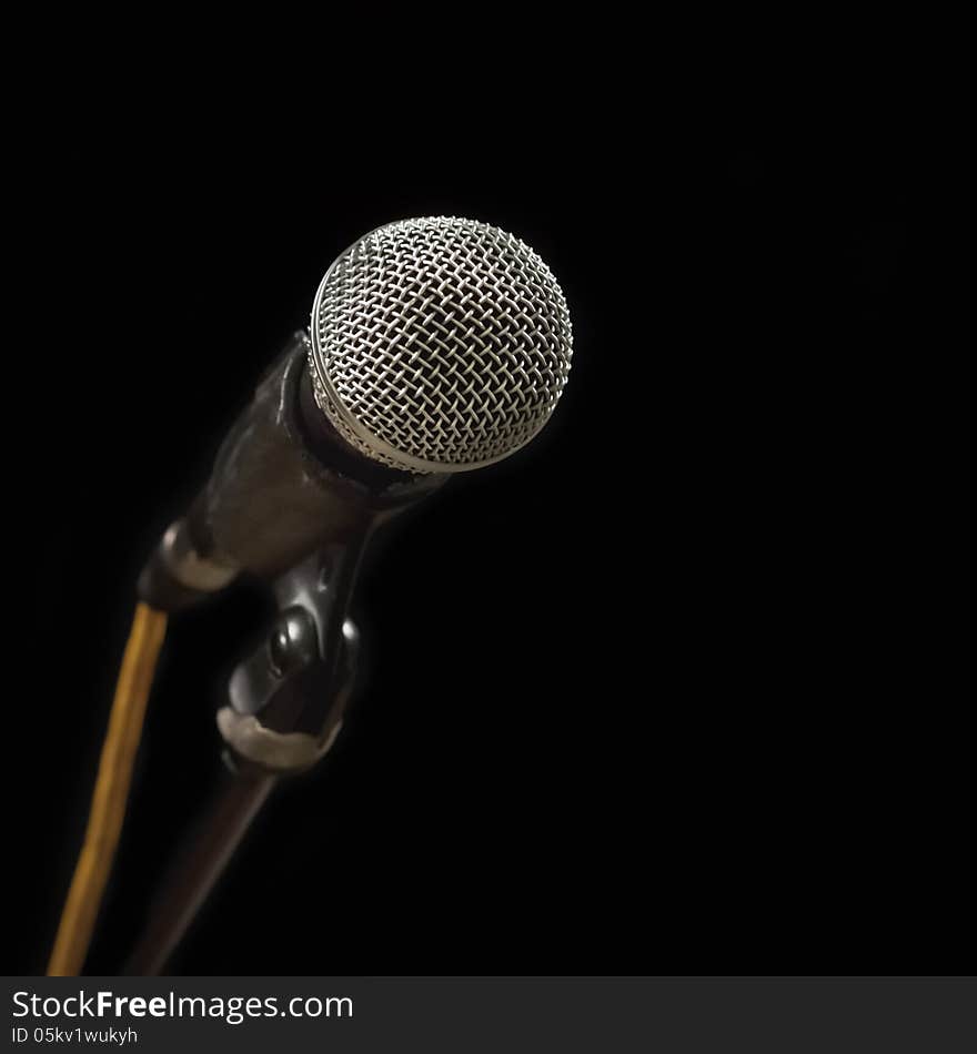 Classic black microphone on black stand. Isolated black background. Classic black microphone on black stand. Isolated black background