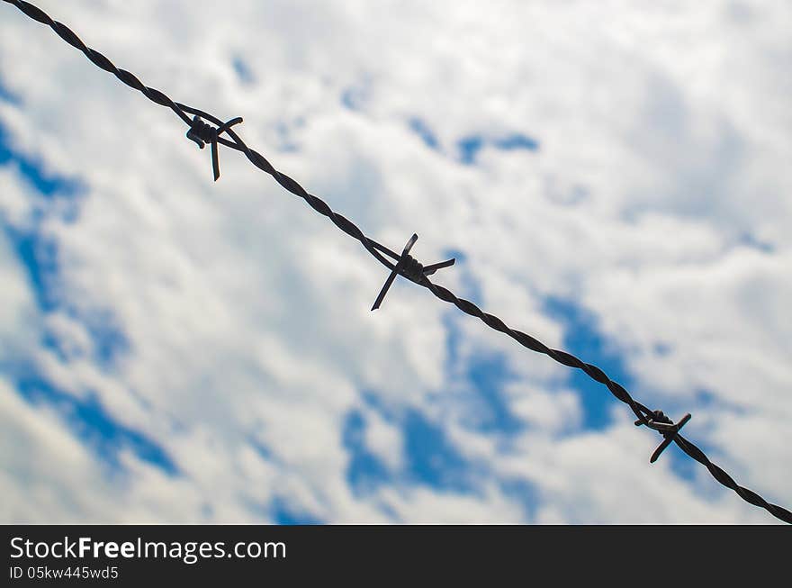 Barbed wires against cloudy sky