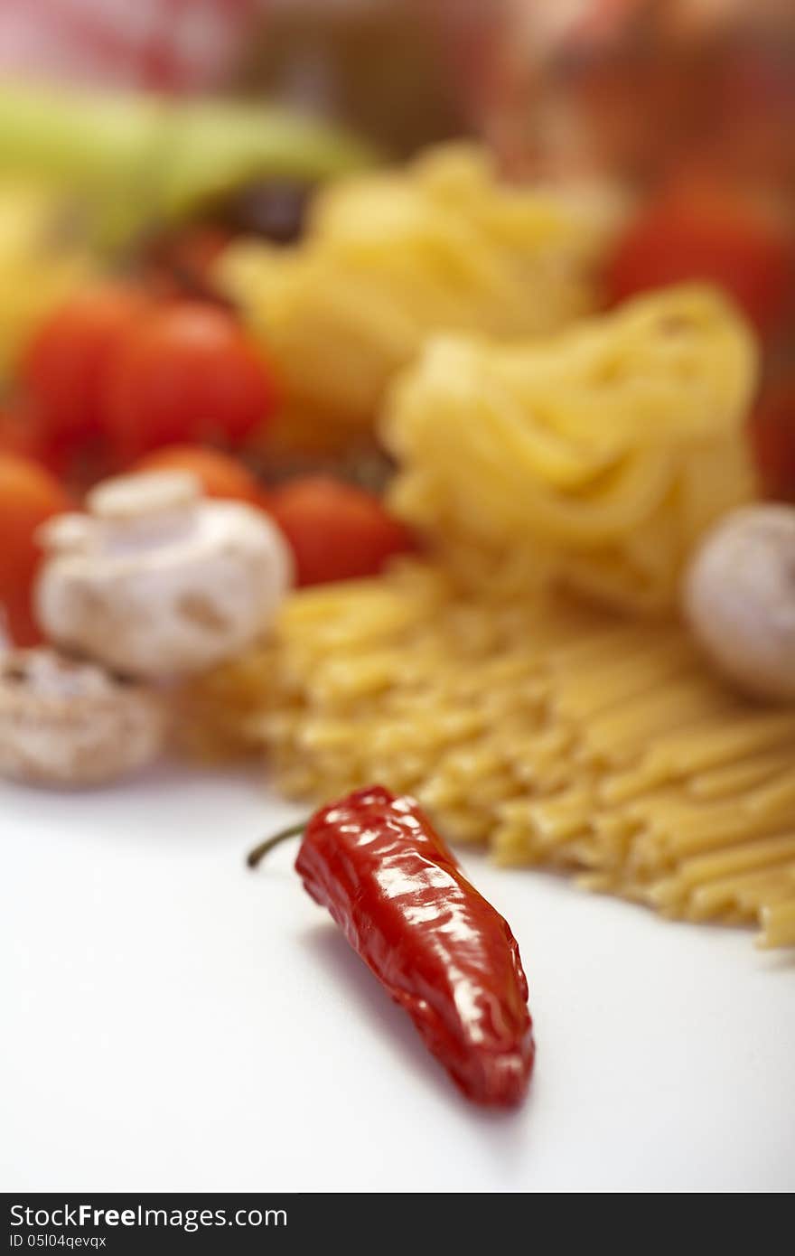 Pepper, spaghetti and vegetables in background