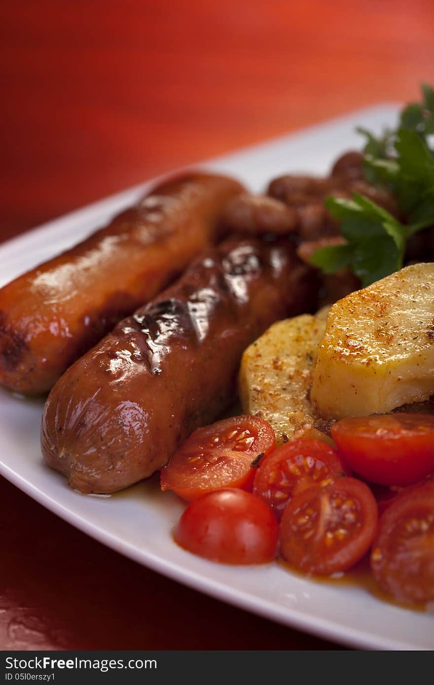 Sausage, potato and tomato on plate. Sausage, potato and tomato on plate