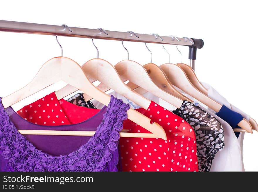 Dresses of different colors on wooden hangers over white