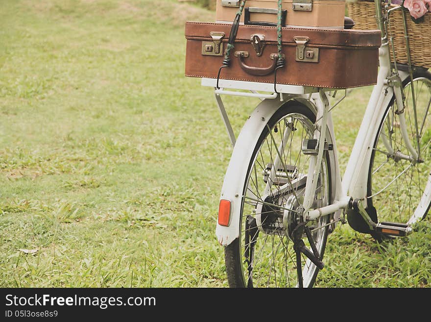 Vintage bicycle on the field with a basket of flowers and bag