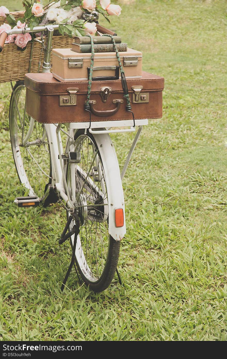 Vintage bicycle on the field with a basket of flowers and bag