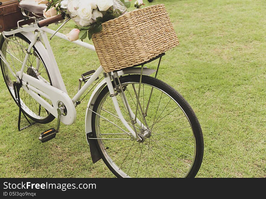 Vintage bicycle on the field with a basket of flowers