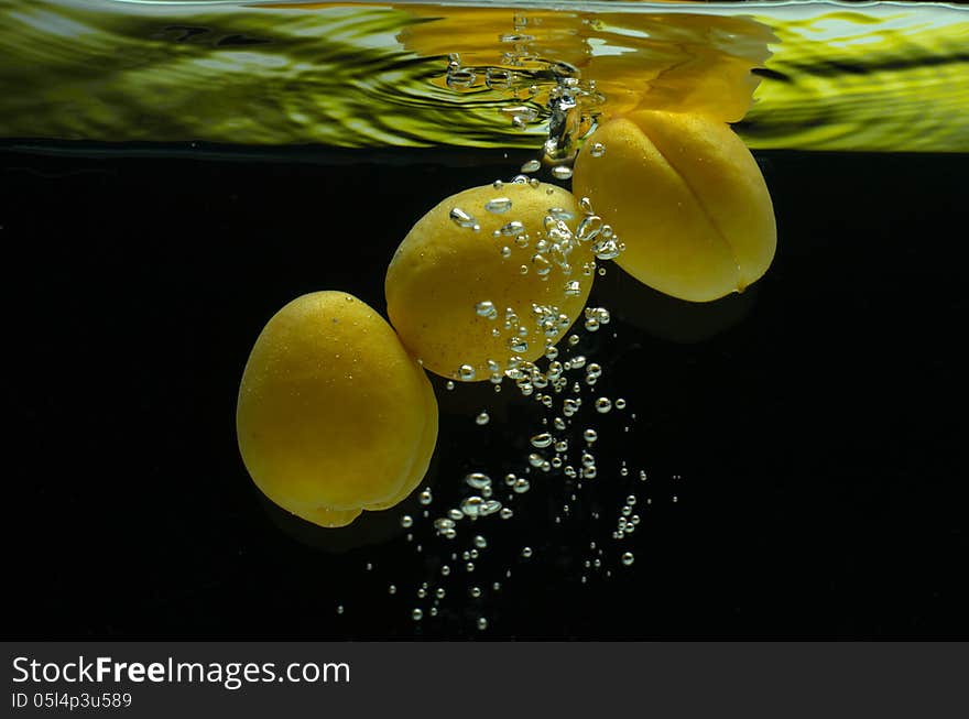 Apricots, fresh air in the water with bubbles on a black background. Apricots, fresh air in the water with bubbles on a black background