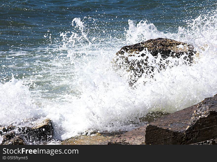 Waves breaking on a stony beach, forming a spray