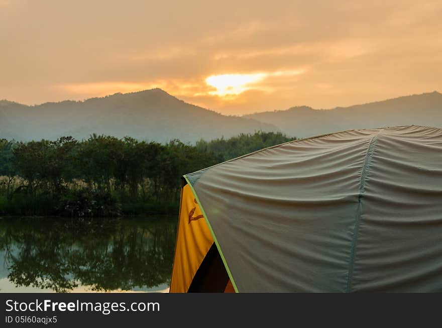 Tent set on the grassland of mountain in the sunrise