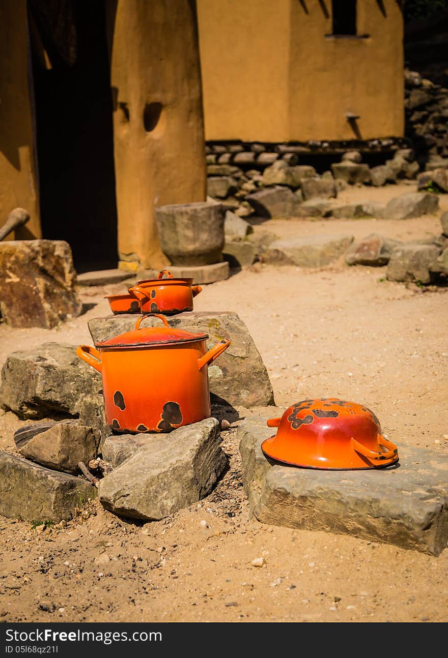 Two old orange pans with lids, together with a old orange bowl and a old orange drainer, drying in the sun ready for use. Two old orange pans with lids, together with a old orange bowl and a old orange drainer, drying in the sun ready for use.