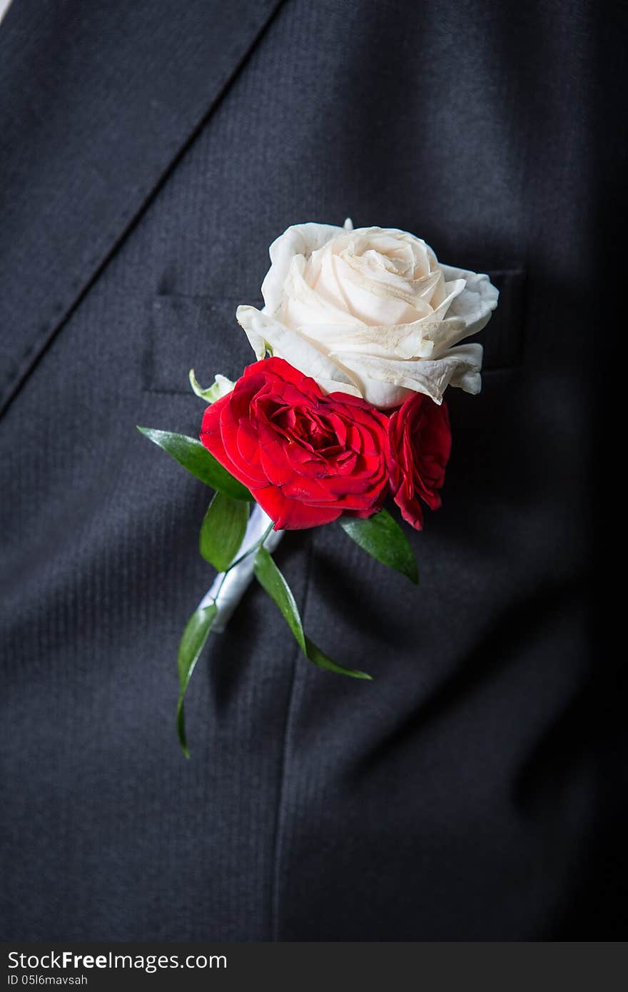 Wedding bouquet of roses on the lapel of his jacket